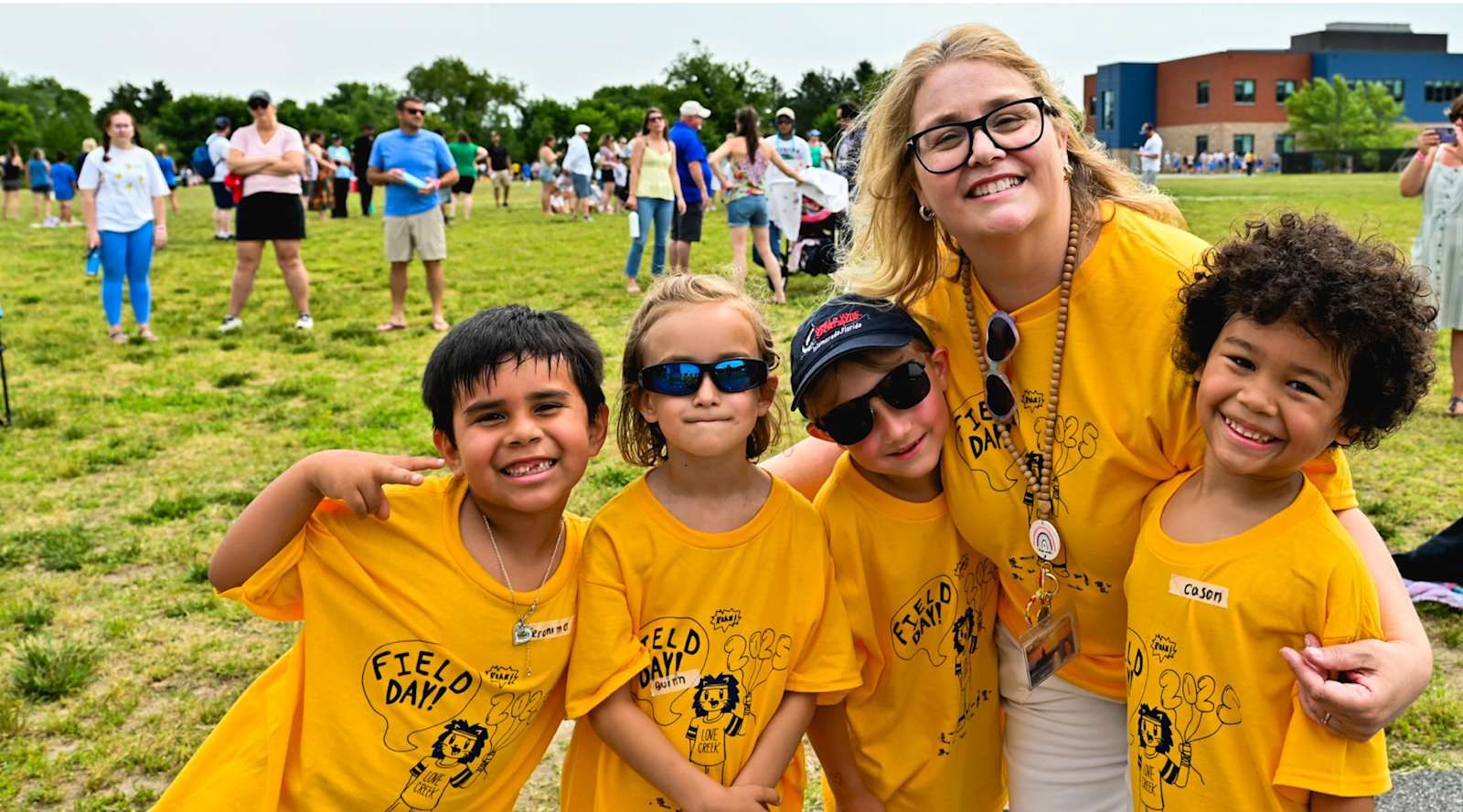 Love Creek Elementary students in yellow field day shirts smiling with their teacher