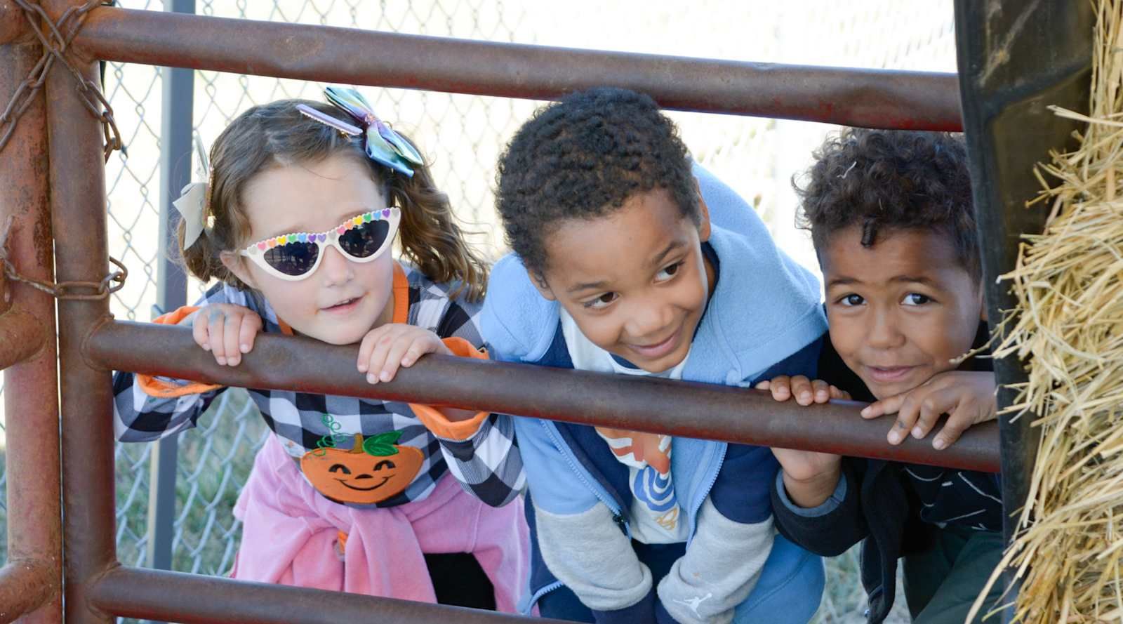 Little Vikings preschoolers peeking through a fence at fall fest